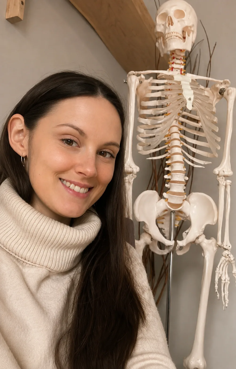 Bryhnn Freitas beside an anatomical skeleton model in her treatment room.